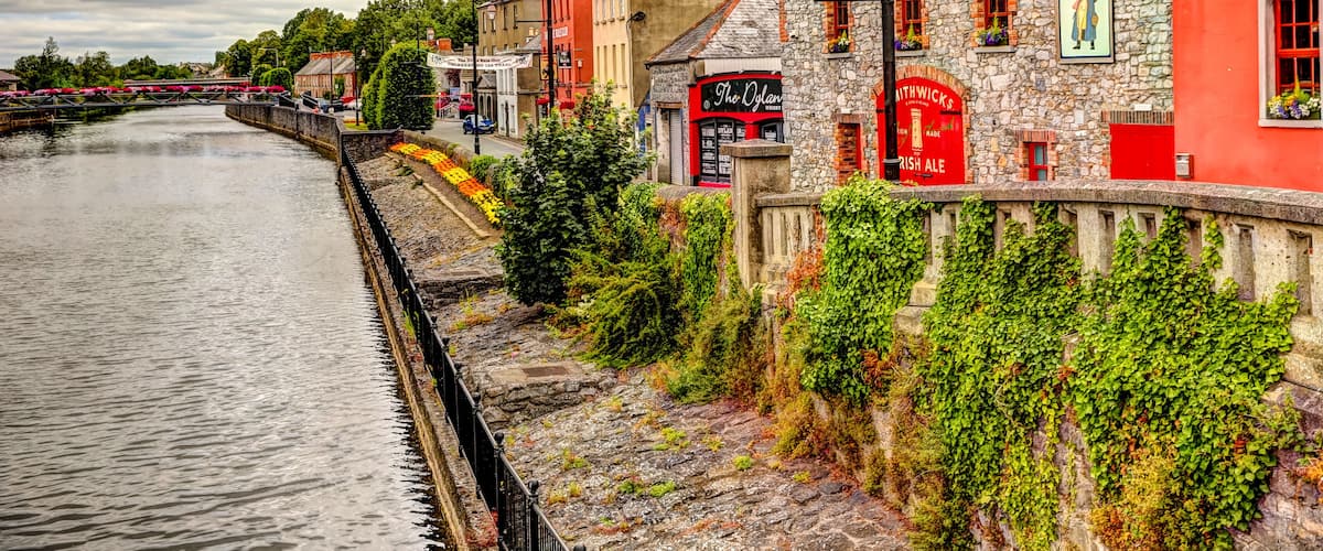A riverside town with stone buildings, a bridge, and a pub named "Matt the Millers Bar & Restaurant".