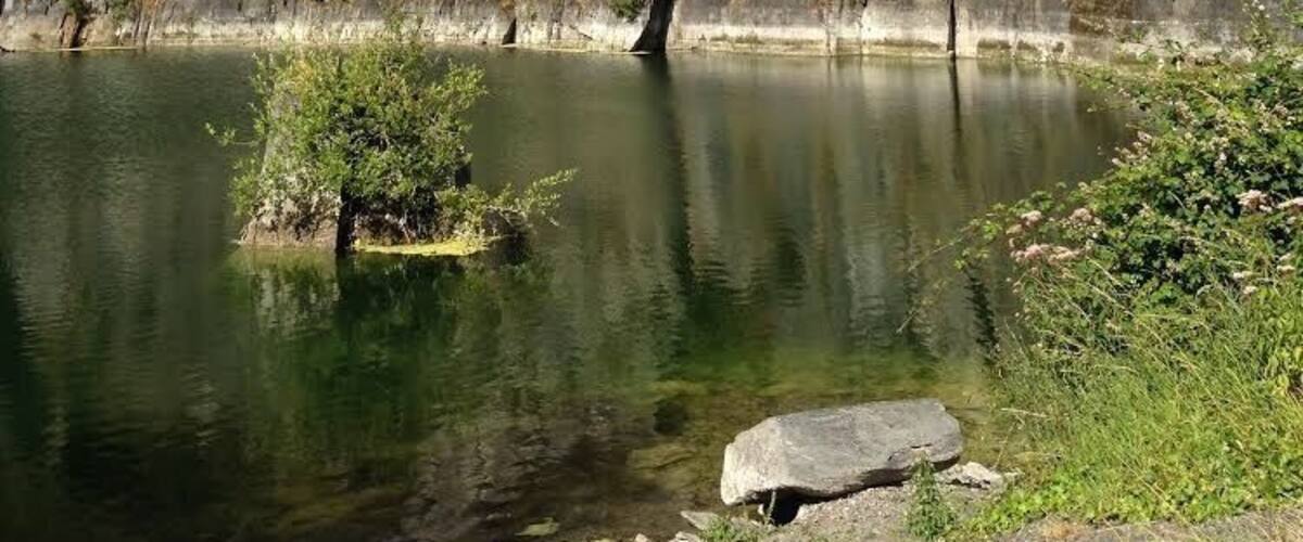 A rocky cliff with a small island in a calm lake.