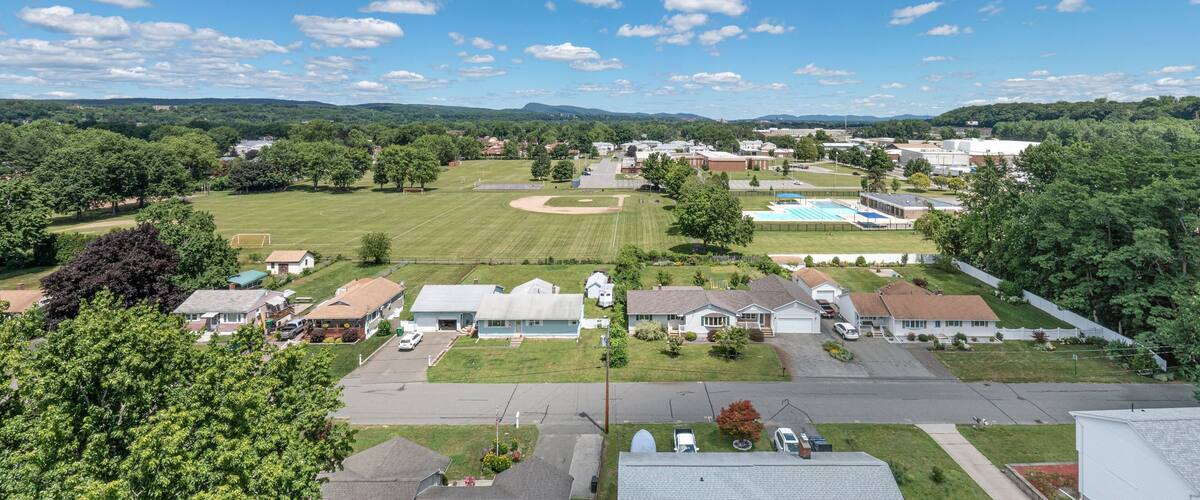 A suburban neighborhood with houses, a baseball field, and a swimming pool.