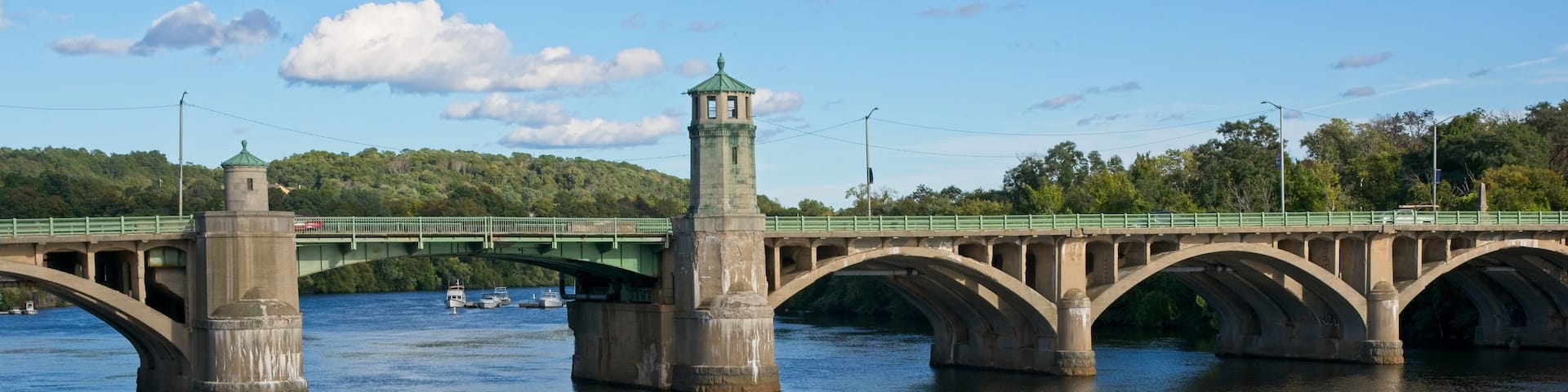 A stone bridge with a tower, green railings, and a river.