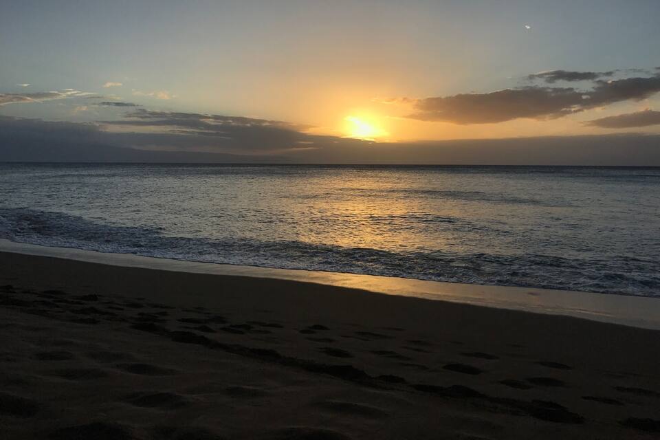 Une plage au coucher du soleil, avec le soleil se reflétant sur l’eau.