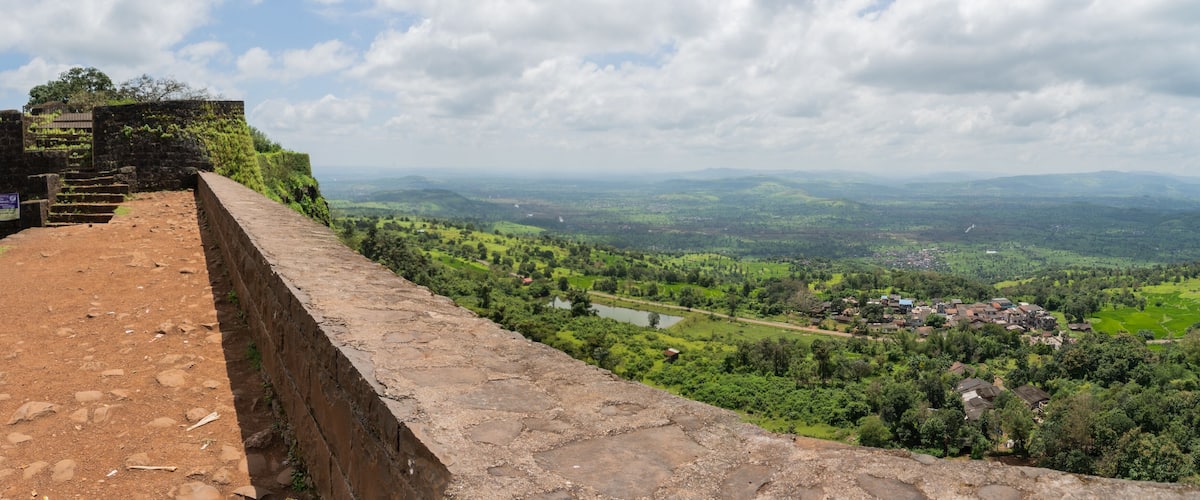 A stone wall with a view of a valley, a river, and distant hills.