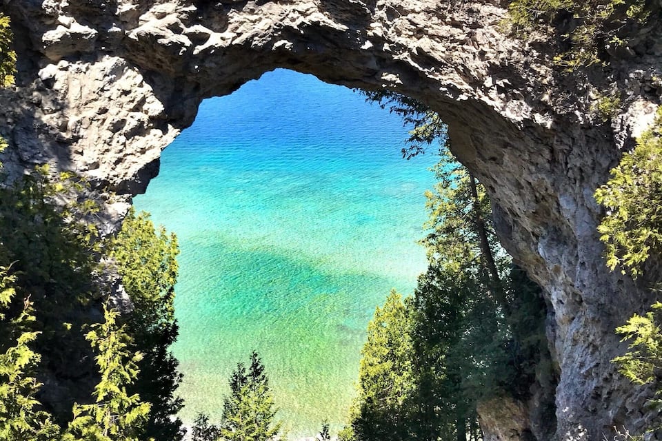 Un arco naturale di roccia con acque turchesi cristalline sottostanti.