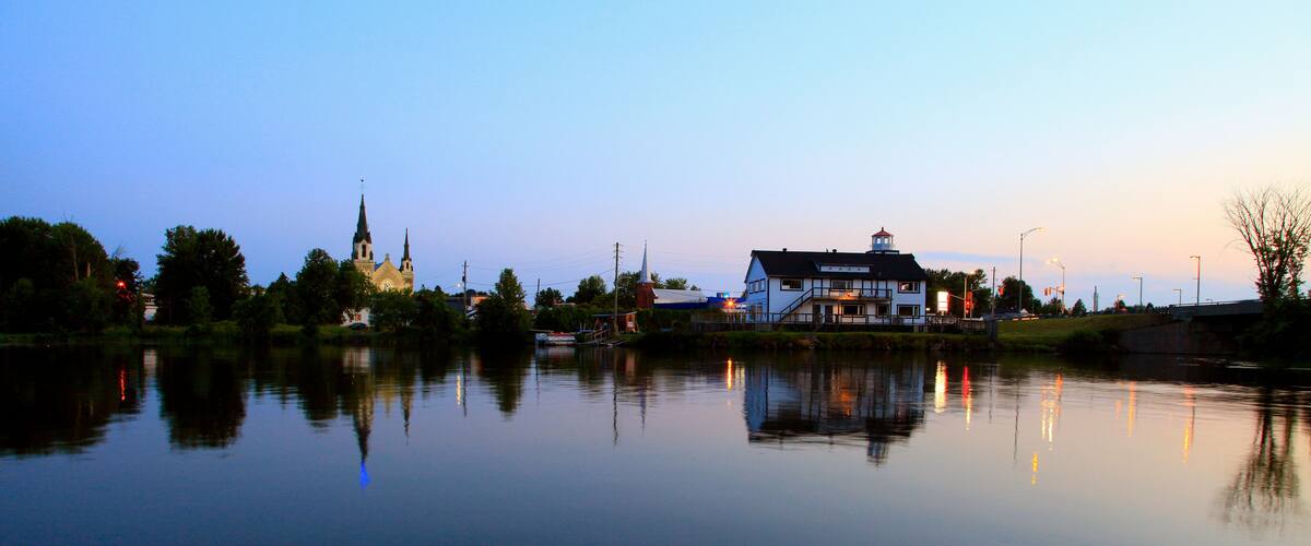 A calm lake with a church and a house reflecting in the water.