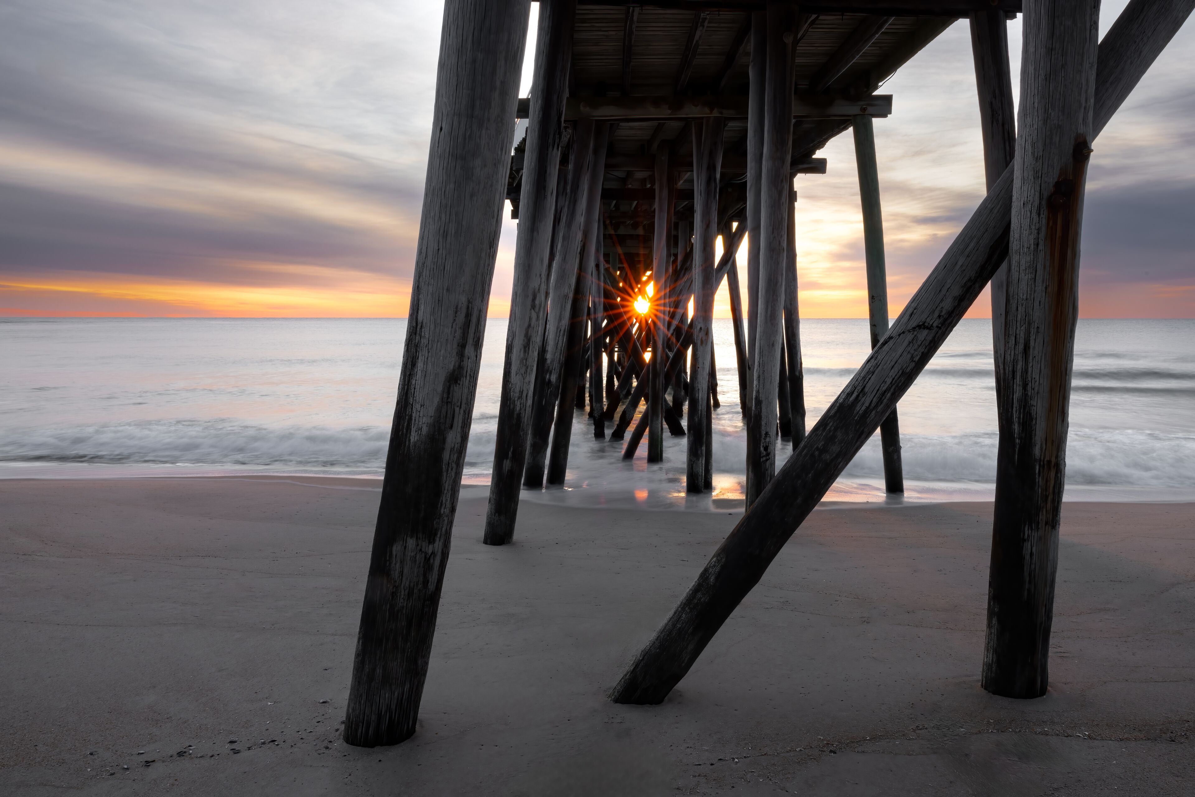 Sunstar at Sunrise Through Wooden Pilings of Belmar Fishing Pier, New Jersey