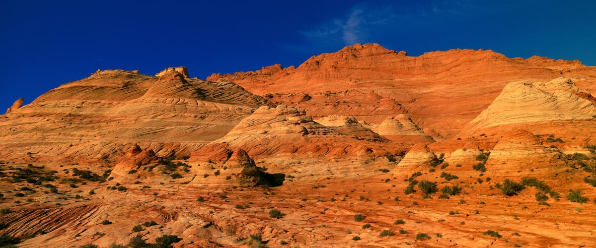 A rugged mountain range with layered rock formations and sparse vegetation.
