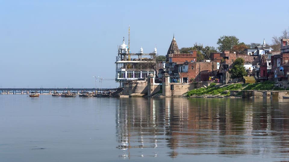 A riverside town with historic buildings and boats on the water.