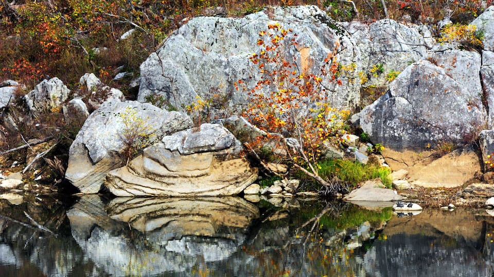 A rocky landscape with a calm body of water reflecting the surroundings.