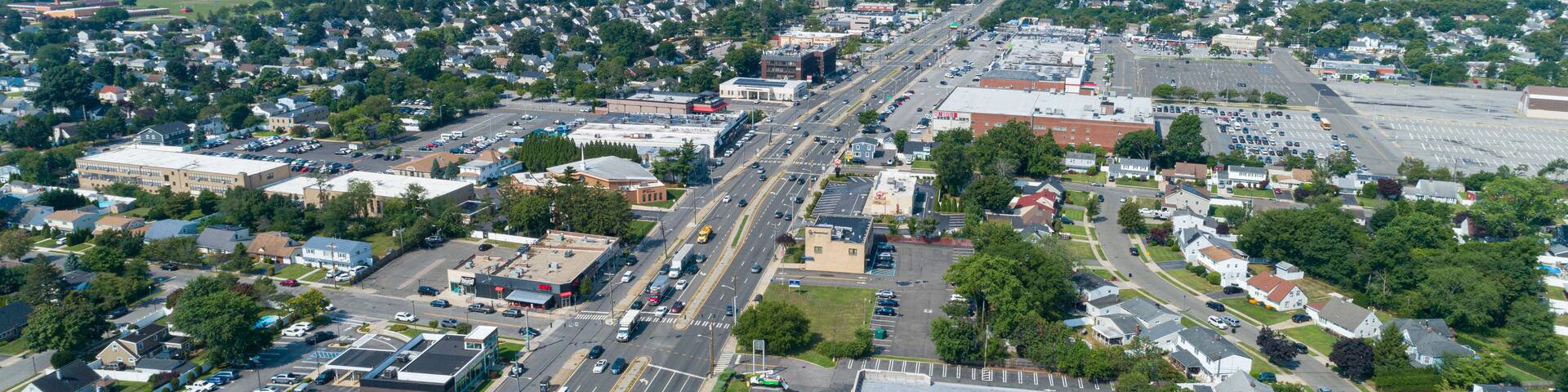 Aerial View of Hempstead Turnpike in Levittown, NY Which is a Busy Urban Area With Shopping Centers and Residential Homes on a Clear Day