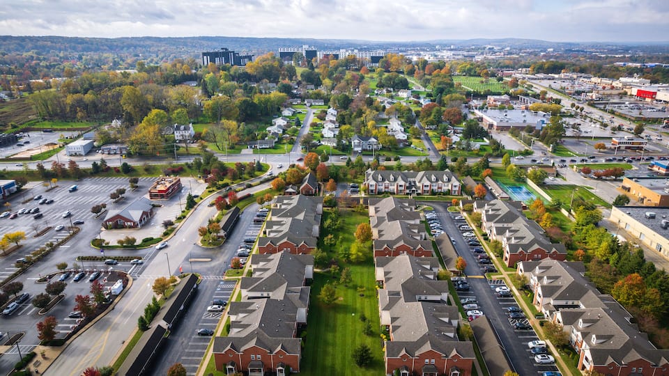 A suburban area with residential buildings, parking lots, and a mix of greenery and urban development.
