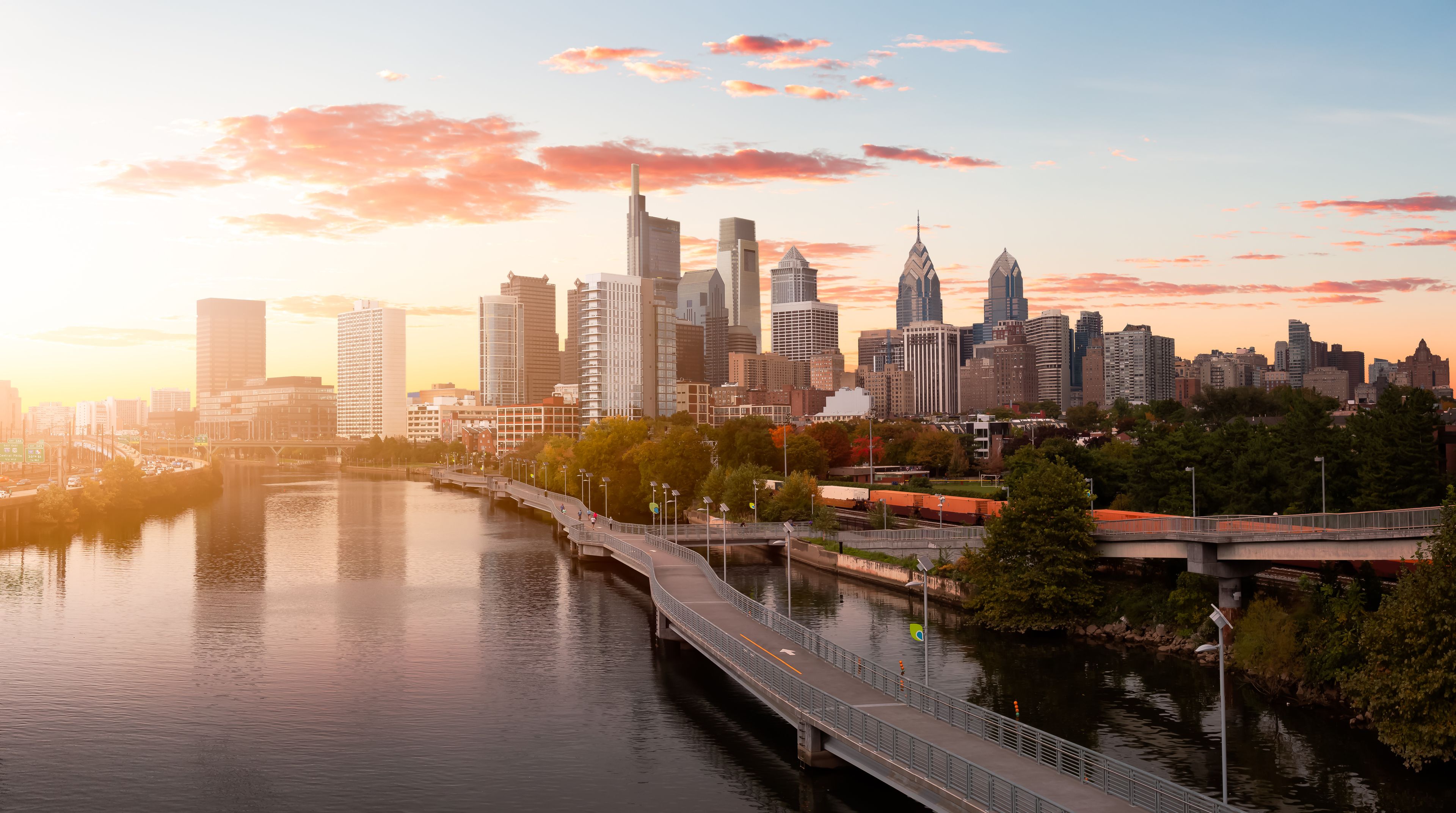 A city skyline with a river, bridges, and a sunset.