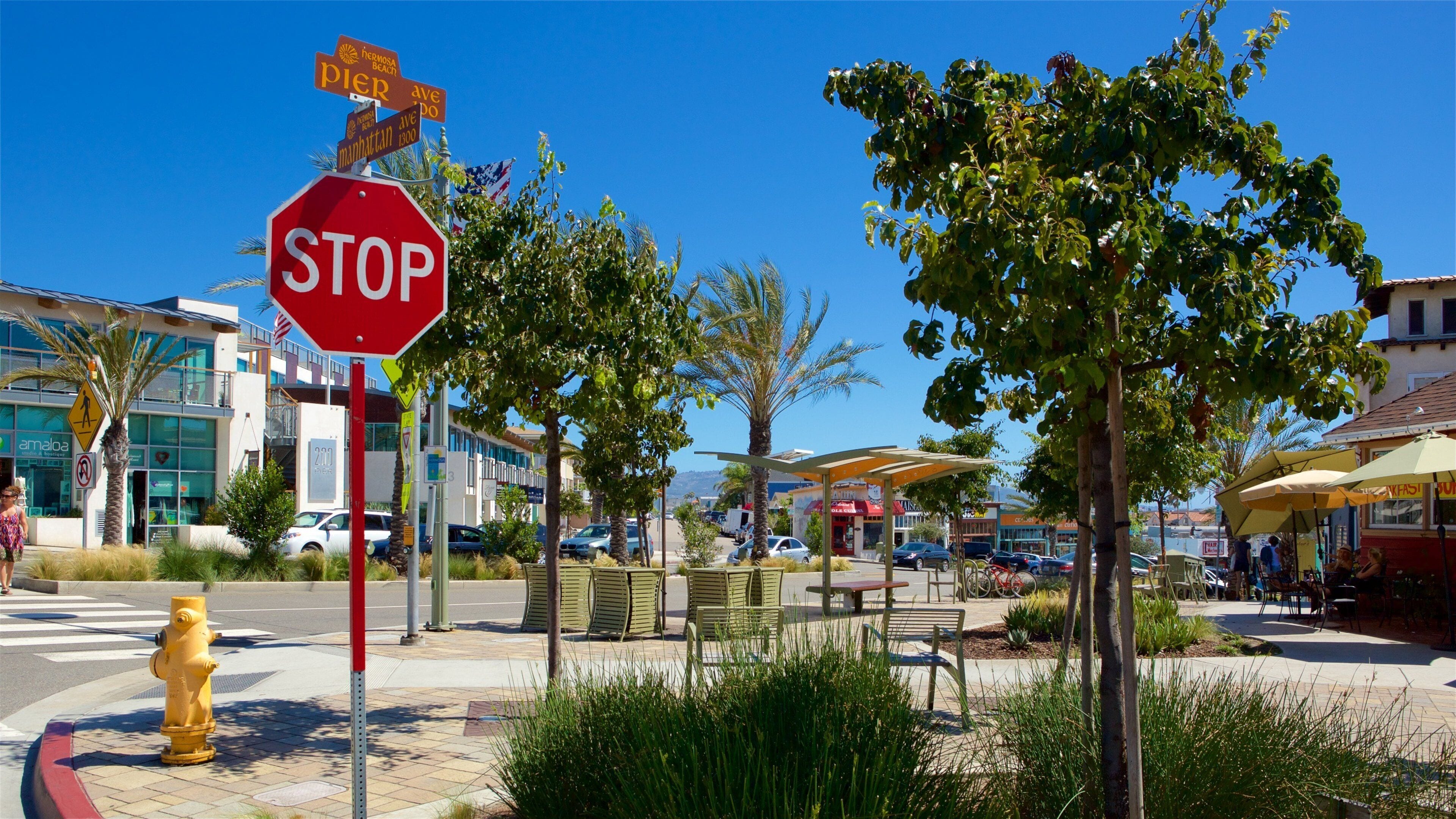 A stop sign, street signs, a pedestrian crossing, a fire hydrant, and a café with outdoor seating.