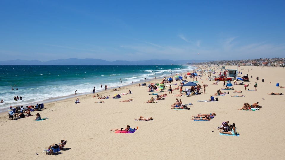 A crowded beach with people sunbathing and swimming.