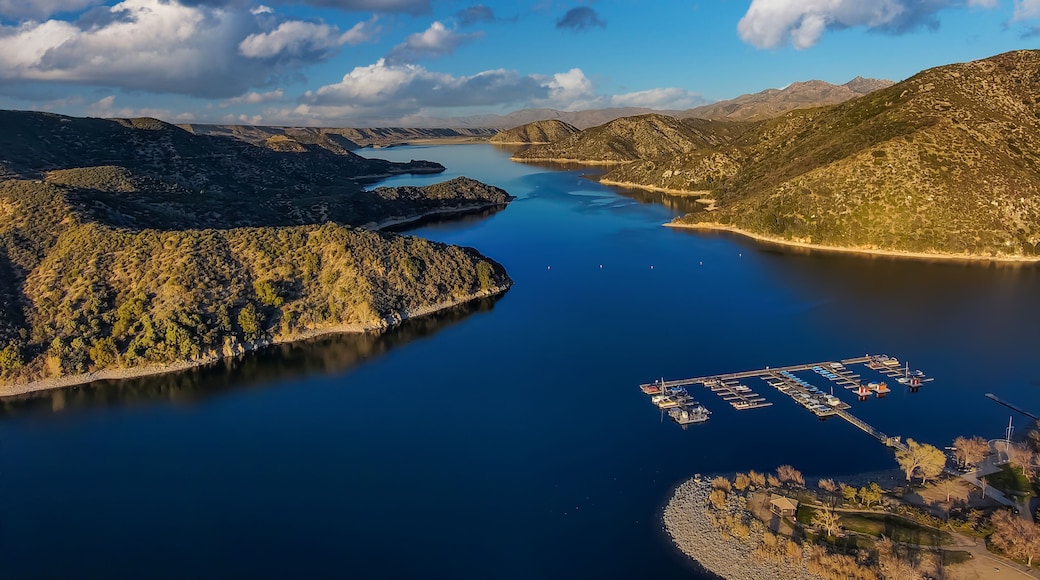 a gorgeous shot of the vast blue lake surrounded by majestic mountain ranges with a boat dock, blue sky and clouds at Silverwood Lake in Hesperia California USA