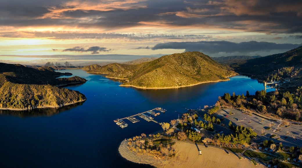 a majestic aerial panoramic shot of the vast blue still lake water with breathtaking mountain ranges reflecting off the lake with powerful clouds at sunset at Silverwood Lake in Hesperia California