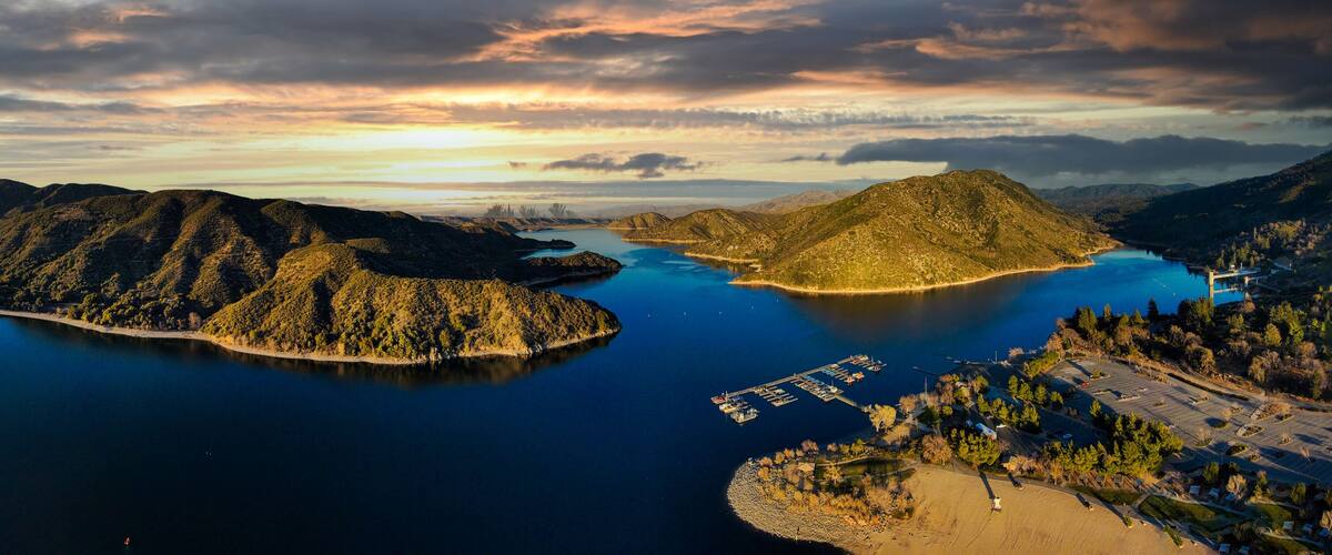 A lake surrounded by mountains, a dock, and a parking area.
