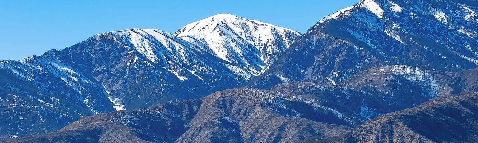 A mountain range with snow-capped peaks and a clear blue sky.