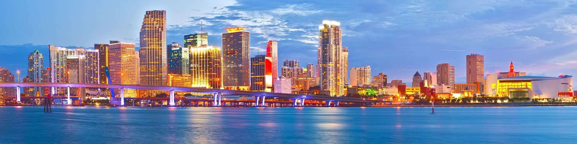 Miami Florida at sunset, cityscape of modern downtown buildings illuminated with reflections in the waters of Biscayne BAy