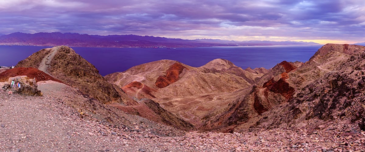 A rugged mountainous landscape with a view of a large body of water and distant mountains.