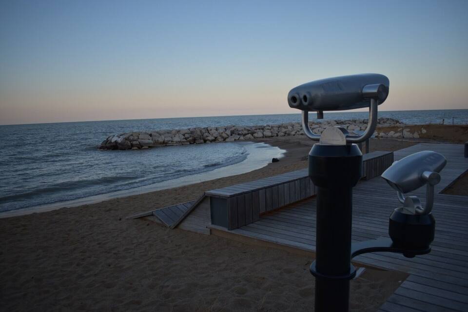 A beach with a wooden boardwalk and a rocky breakwater.