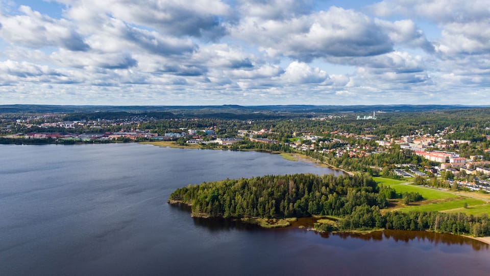A lake surrounded by a town with buildings and greenery.