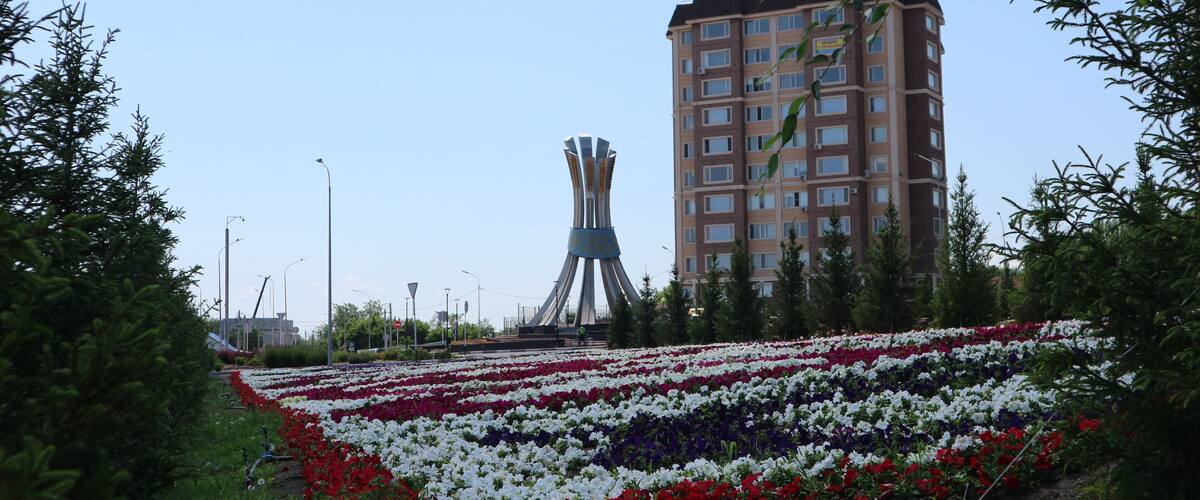 A flower garden with a tall building in the background.
