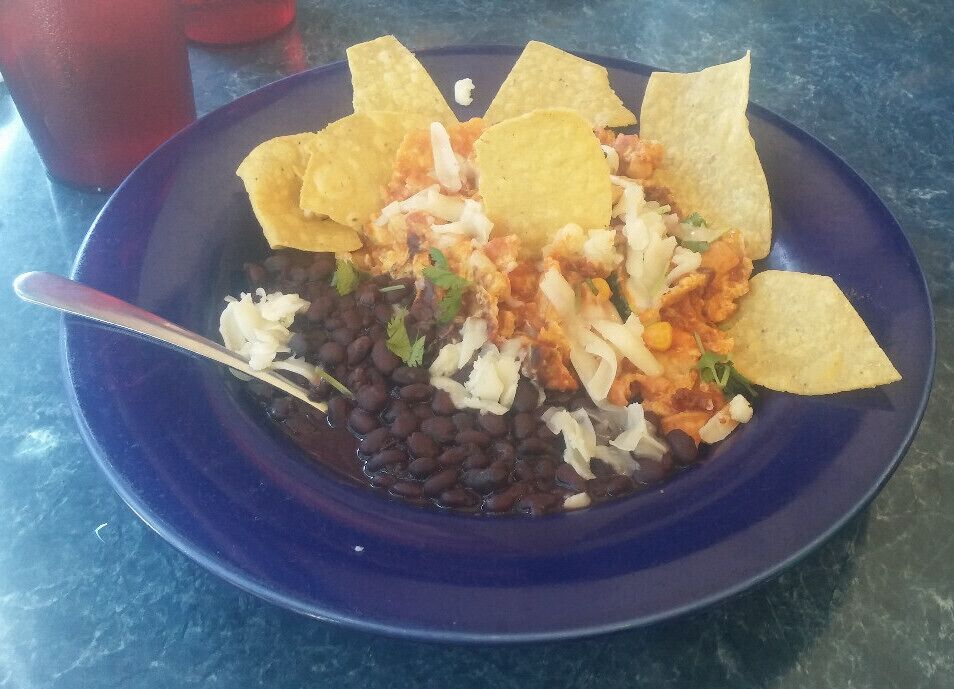 Chiliquiles; Eggs scrambled with chorizo, peppers, onions, corn, zucchini, tortilla chips, all tossed with a smoked chile cream sauce, jack cheese & cilantro, served with black beans.