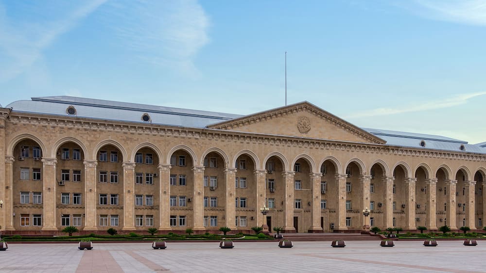 Ganja City Hall in Azerbaijan, a large beige building with an arched facade. It has many windows and a central entrance. A big plaza lies in front of it