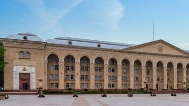 Ganja City Hall in Azerbaijan, a large beige building with an arched facade. It has many windows and a central entrance. A big plaza lies in front of it