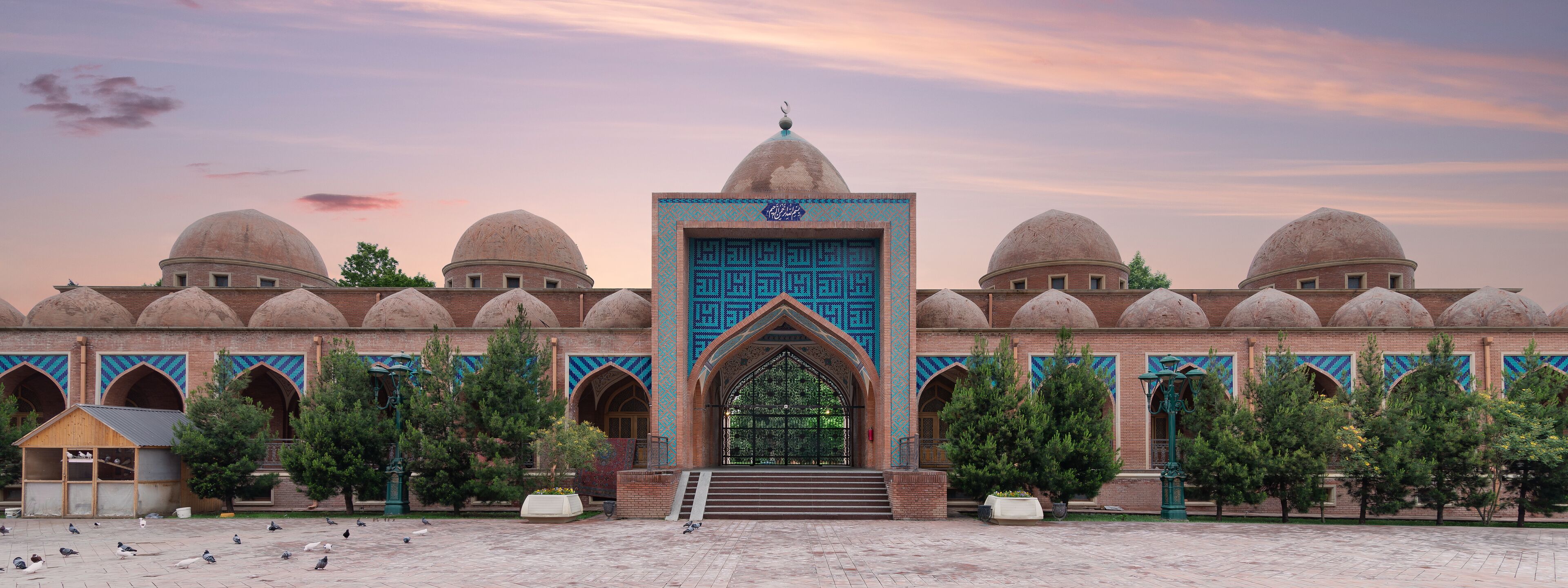 The Imamzadeh Mosque in Ganja, Azerbaijan, features a large courtyard with a central entranceway. The mosque has several domes and intricate tile work