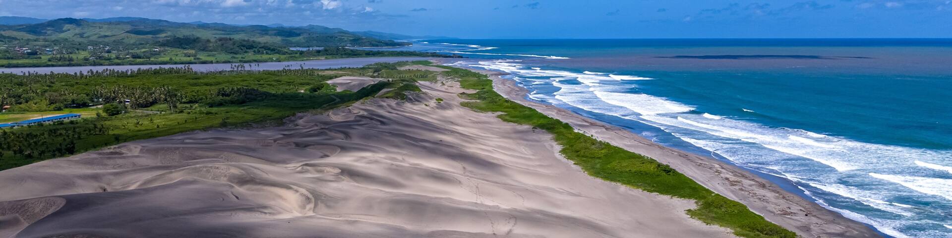 Drone view focusing on the beautiful curves and geological formations of the Sigatoka Sand Dunes in Fiji as they meet the coastline