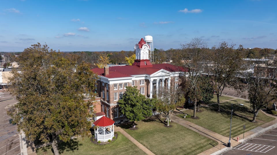A large brick building with a red roof and a clock tower.
