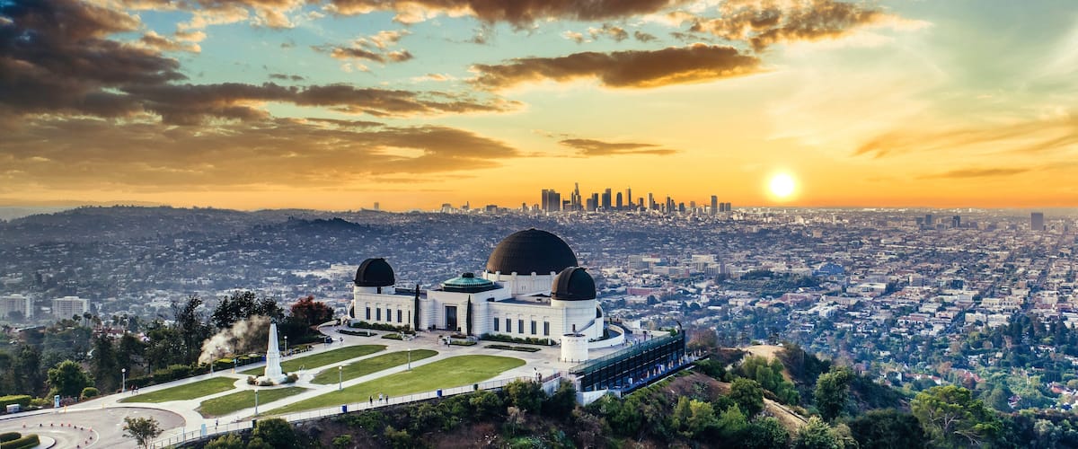 A cityscape with a large observatory featuring domes, surrounded by greenery and a clear sky.