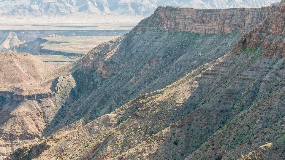 A rugged canyon landscape with steep cliffs and sparse vegetation.