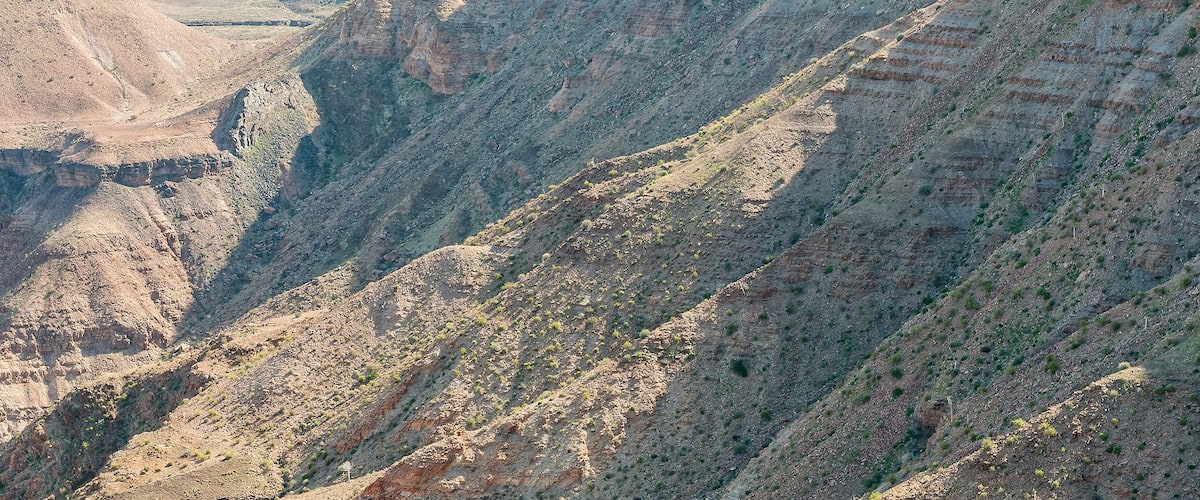 A rugged canyon landscape with steep cliffs and sparse vegetation.
