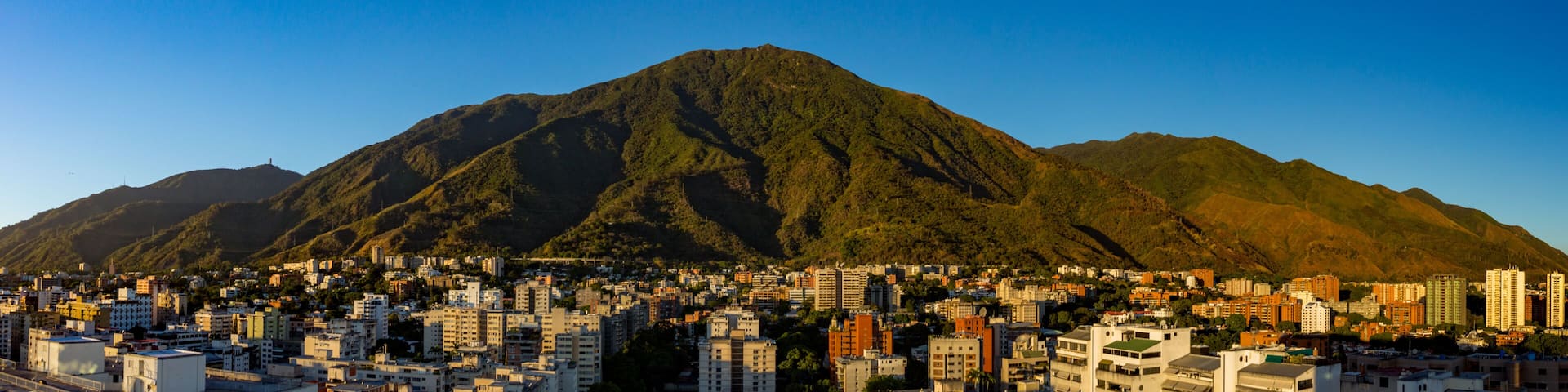 A cityscape with a prominent mountain in the background.