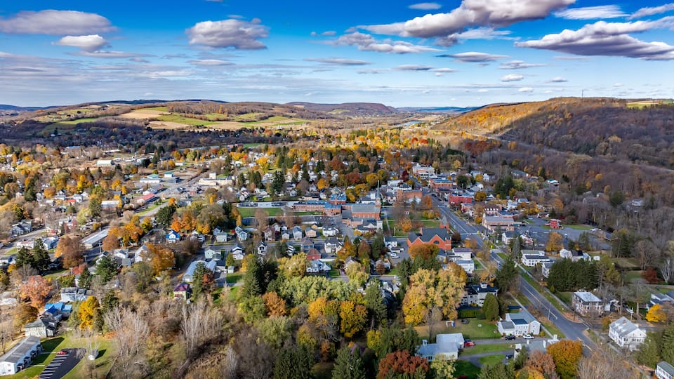 A town surrounded by autumn-colored trees and rolling hills.