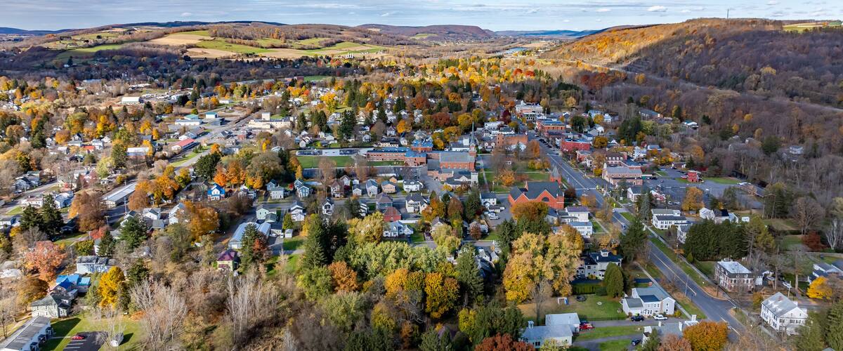 A town surrounded by autumn-colored trees and rolling hills.