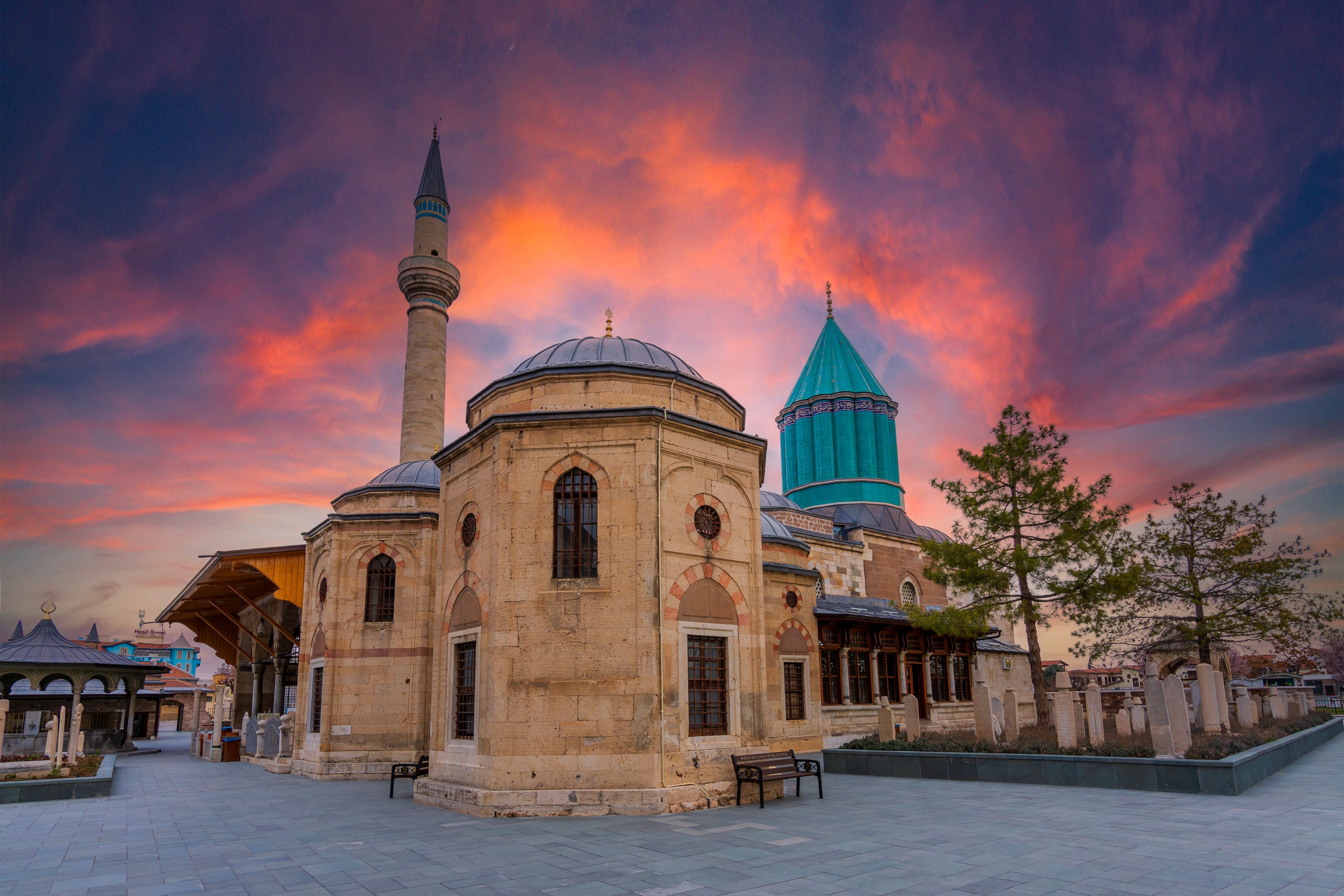 Una mezquita histórica con un minarete y una cúpula destacados, frente a un cielo vibrante al atardecer.