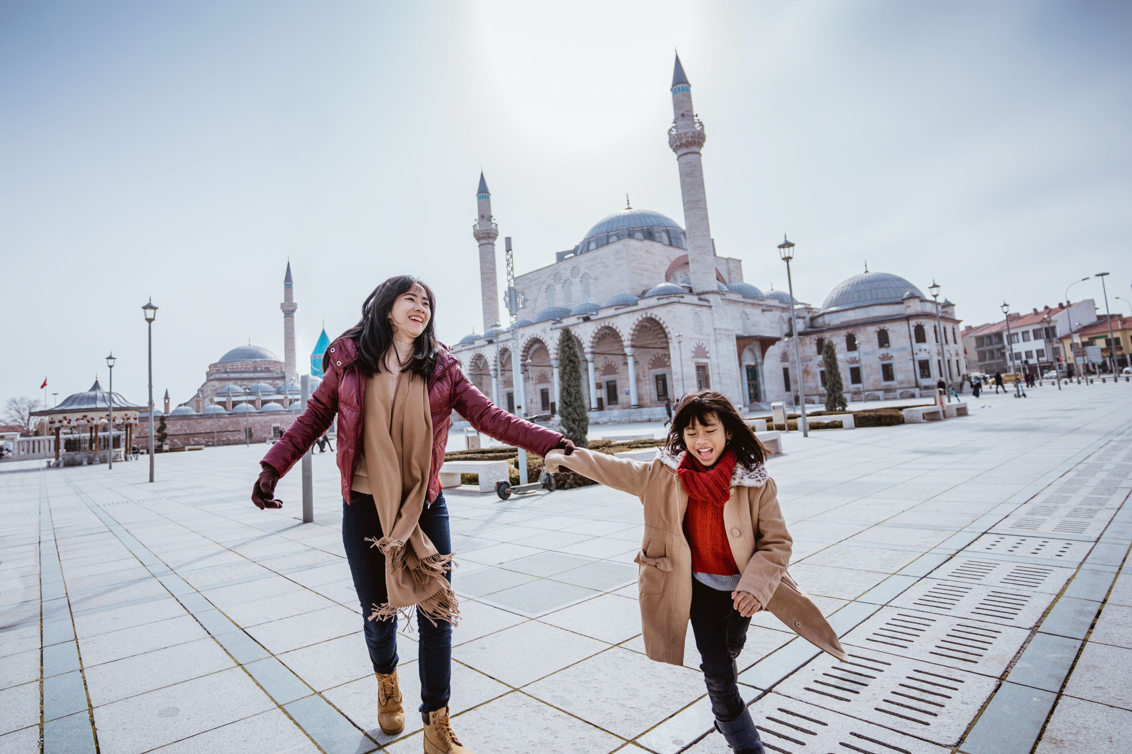 mother playing around with her daughter in the square while visiting mosque in konya turkiye