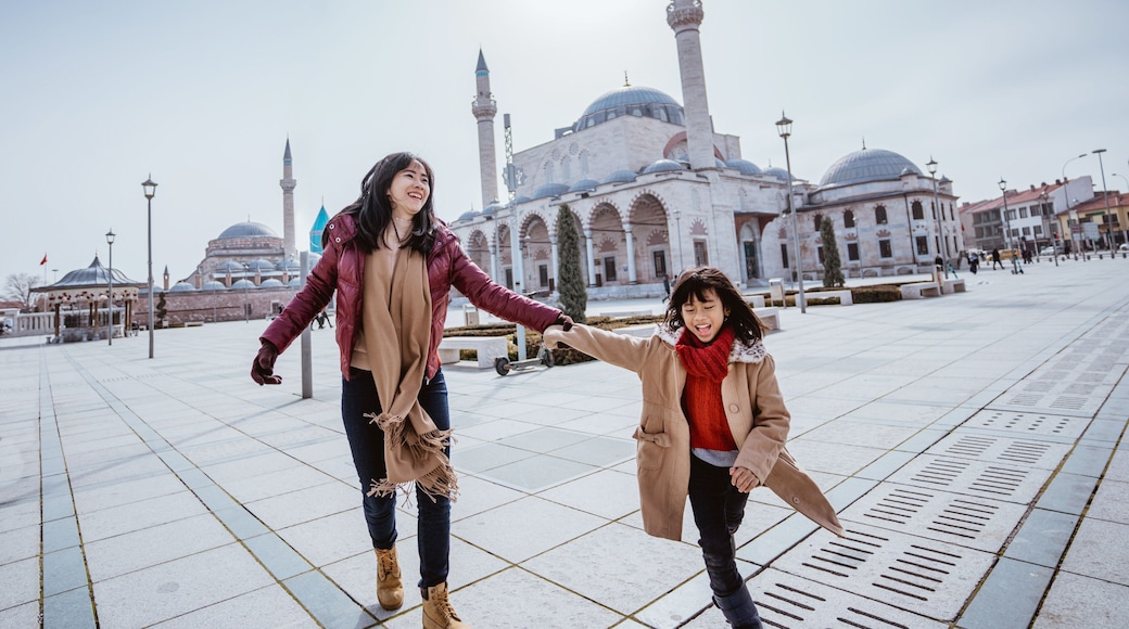 mother playing around with her daughter in the square while visiting mosque in konya turkiye