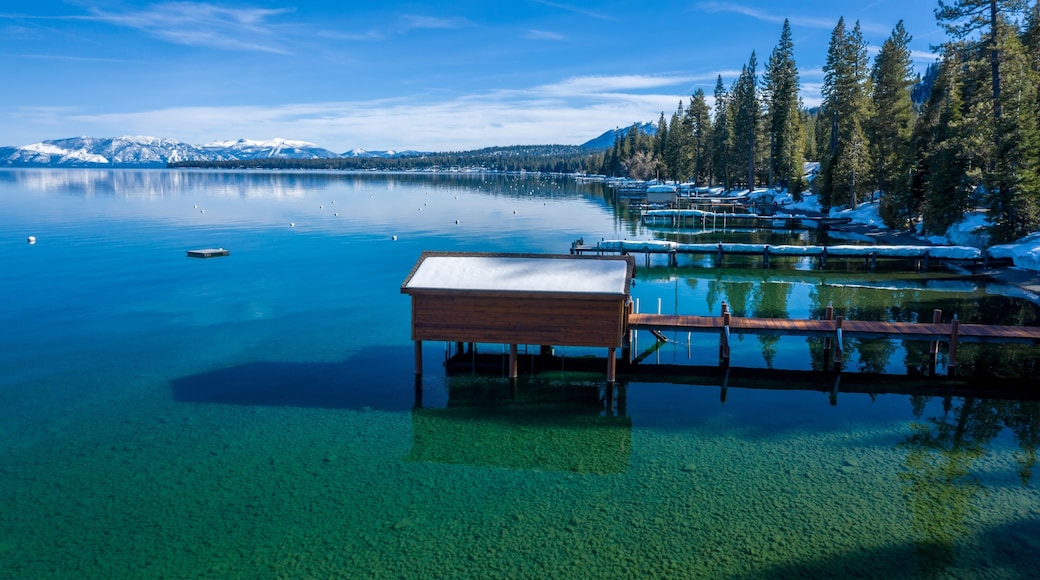 Pier, mountains with snow on calm Lake Tahoe, Homewood, California, United States of America.
