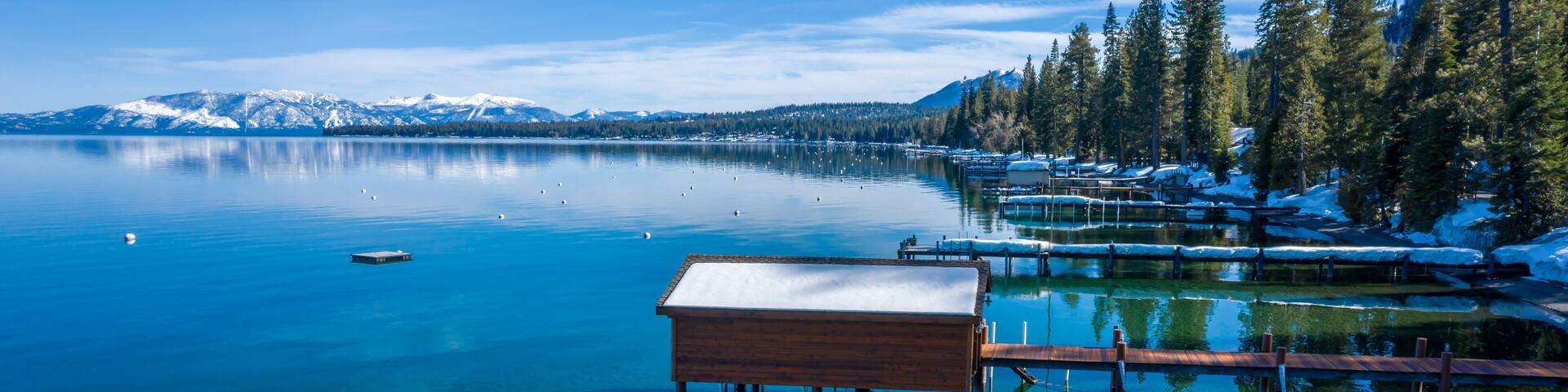 Pier, mountains with snow on calm Lake Tahoe, Homewood, California, United States of America.