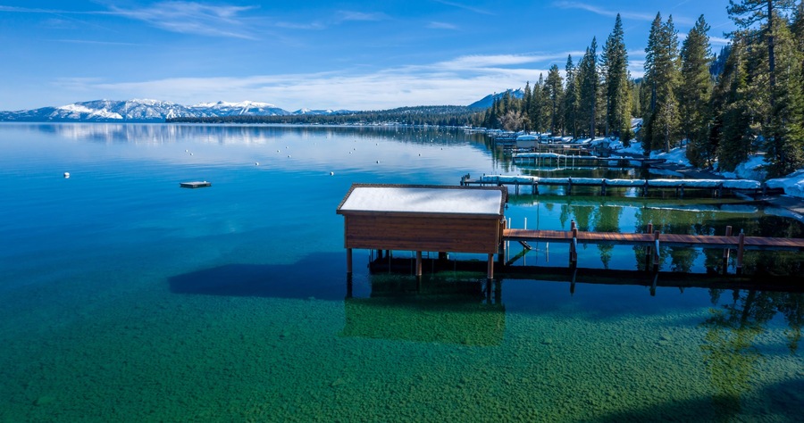 Pier, mountains with snow on calm Lake Tahoe, Homewood, California, United States of America.