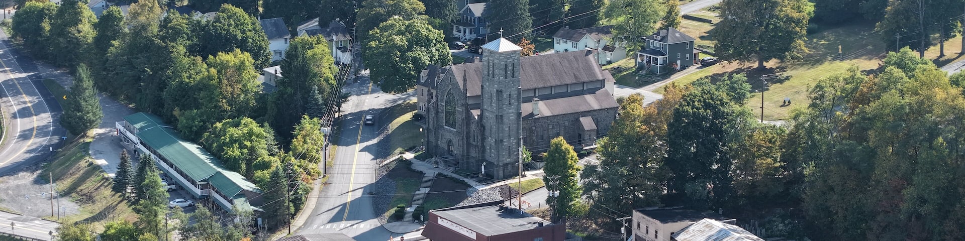 An aerial view of a town with a prominent church, residential houses, and a parking lot.