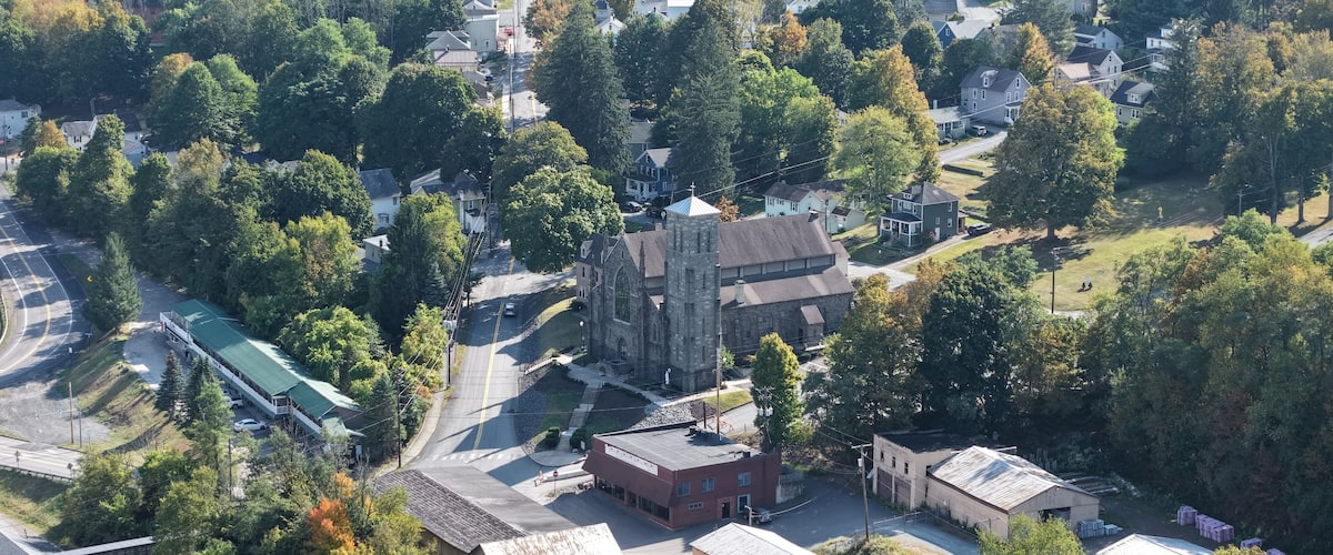An aerial view of a town with a prominent church, residential houses, and a parking lot.