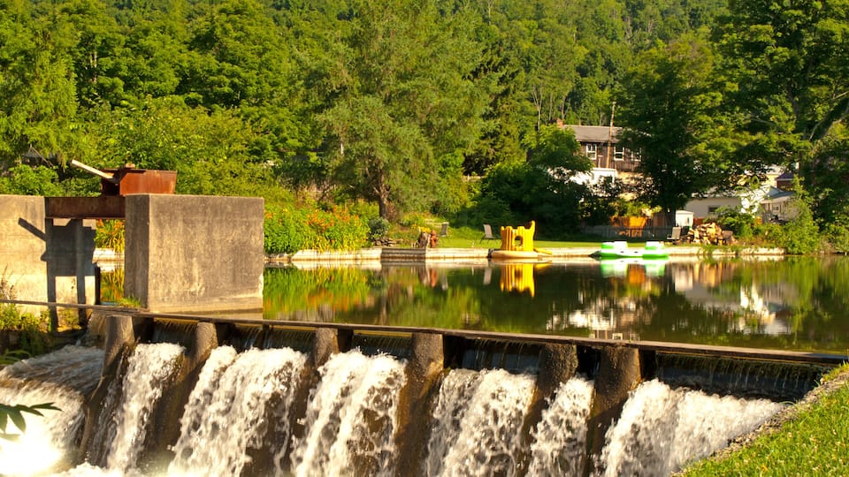 A waterfall, a calm lake, and a forested hillside.