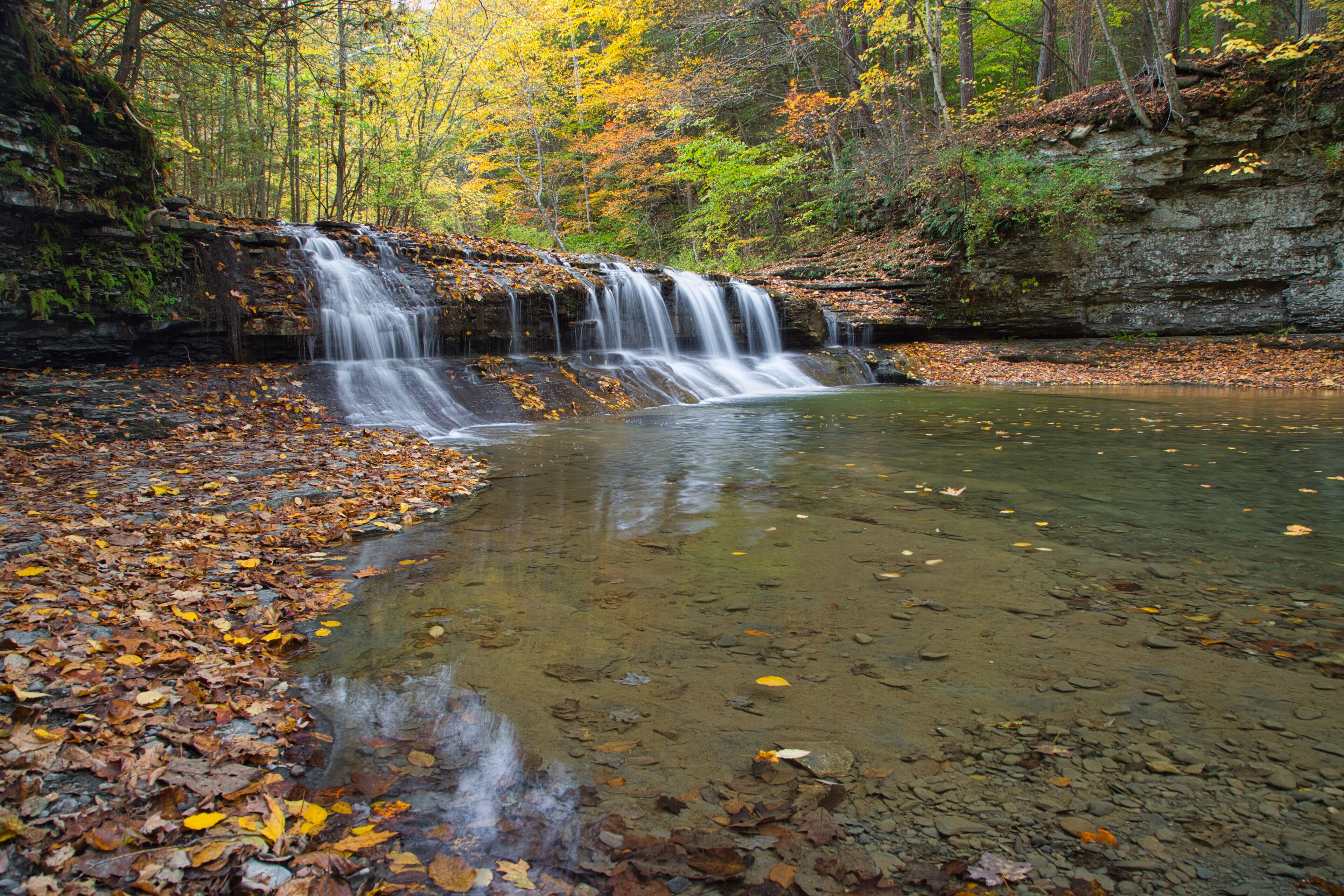 Small waterfall surrounded by the forest in autumn in Robert H. Treman State Park, NYC, USA