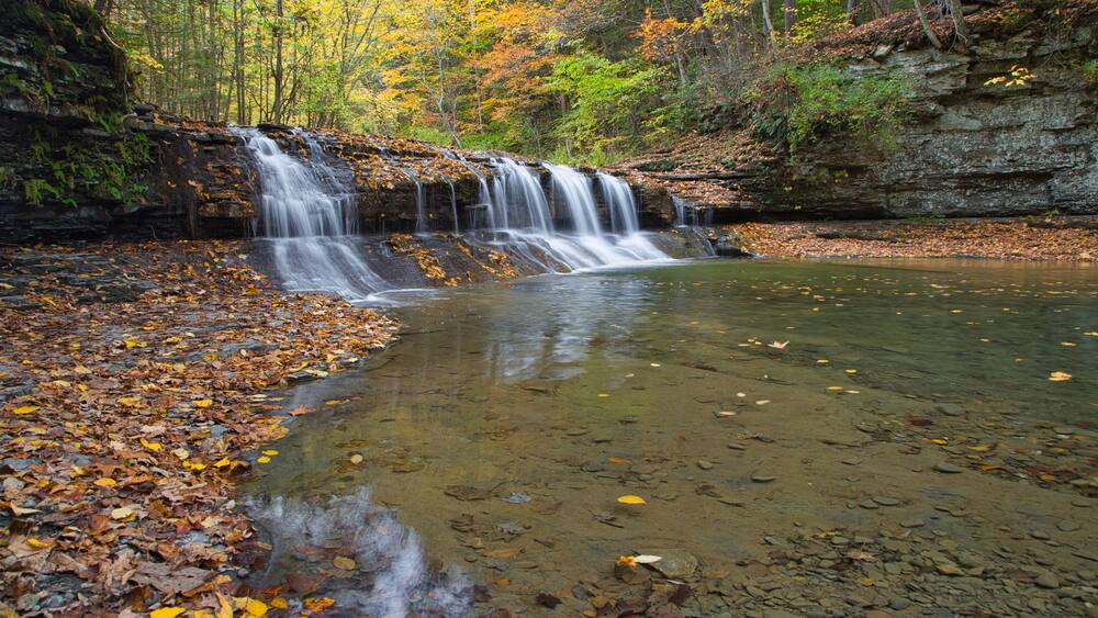 Small waterfall surrounded by the forest in autumn in Robert H. Treman State Park, NYC, USA