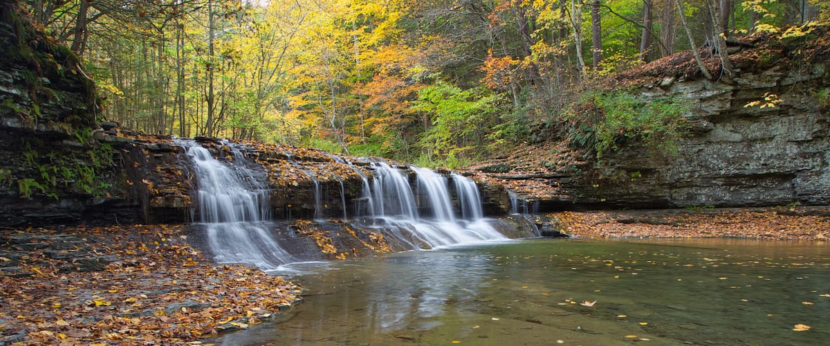 Small waterfall surrounded by the forest in autumn in Robert H. Treman State Park, NYC, USA